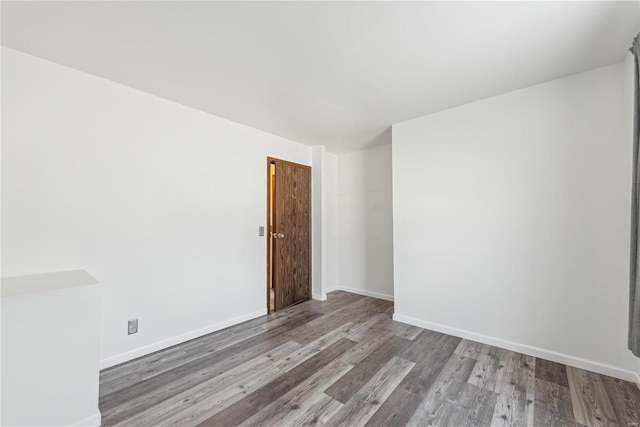 spare room featuring baseboards and wood finished floors