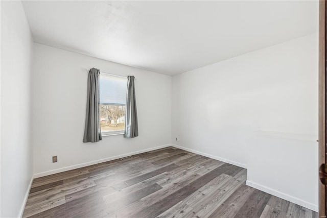 spare room with wood finished floors, visible vents, and baseboards