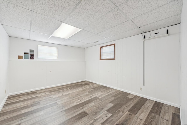 below grade area with a drop ceiling, wood finished floors, and a healthy amount of sunlight