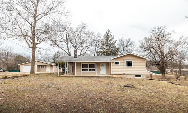 back of house featuring a chimney, a porch, a detached garage, and an outdoor structure