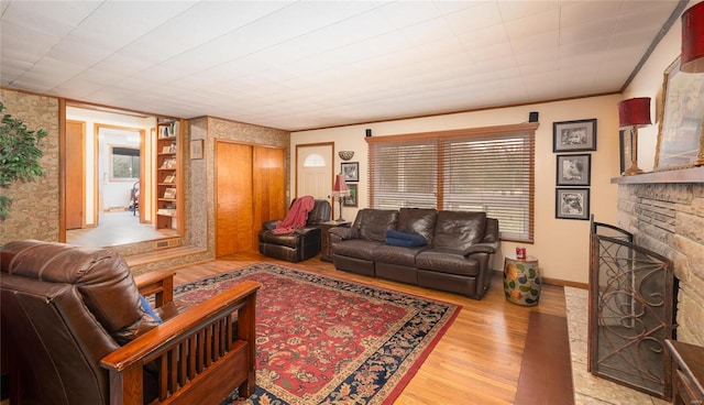 living area featuring baseboards, a fireplace, ornamental molding, and wood finished floors