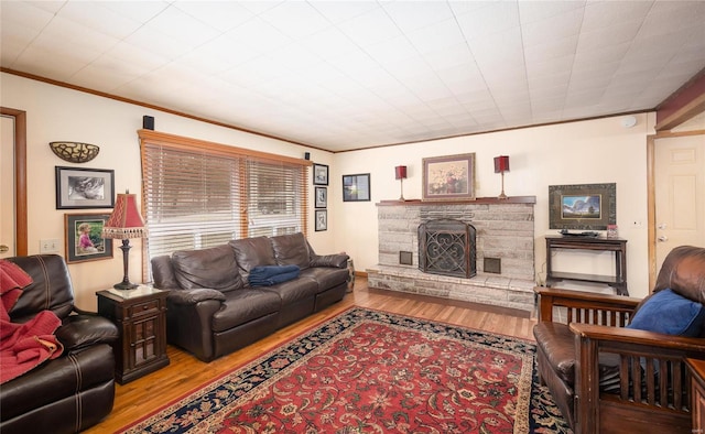 living area with ornamental molding, a fireplace, and wood finished floors