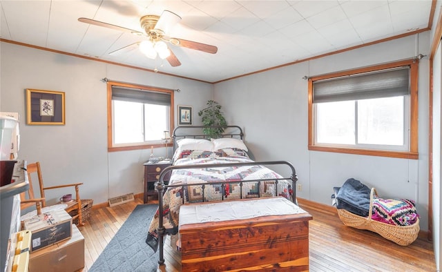 bedroom with ornamental molding, hardwood / wood-style flooring, visible vents, and a ceiling fan