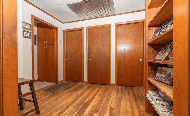 interior space with crown molding, wood finished floors, visible vents, and multiple closets