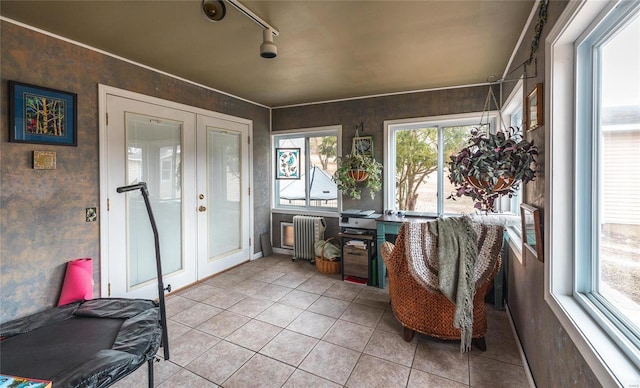 sunroom / solarium featuring radiator, french doors, and track lighting