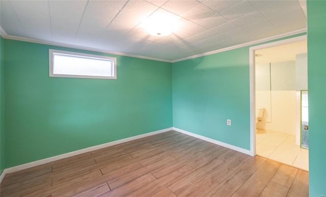 empty room with ornamental molding, baseboards, and wood finished floors