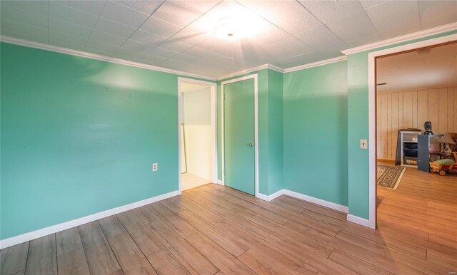 spare room with ornamental molding, baseboards, and wood finished floors