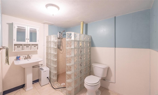 full bath with tile walls, toilet, a sink, walk in shower, and tile patterned floors