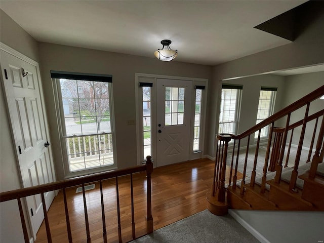 foyer entrance with stairs, visible vents, baseboards, and wood finished floors