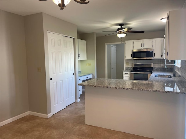 kitchen with light stone counters, stainless steel appliances, decorative backsplash, a ceiling fan, and white cabinetry