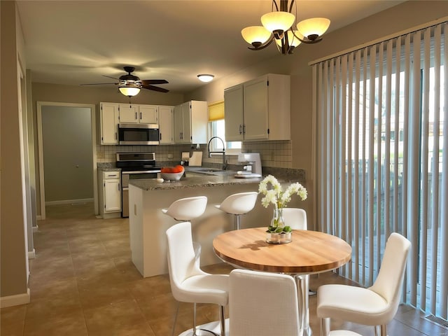 kitchen with stainless steel appliances, tasteful backsplash, light tile patterned flooring, a sink, and a peninsula