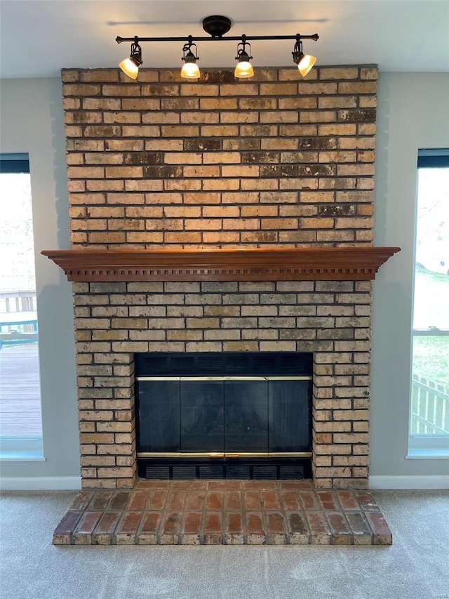 interior details featuring a brick fireplace, baseboards, and carpet flooring