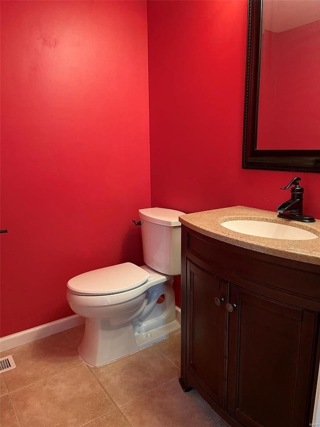 half bath featuring tile patterned flooring, toilet, visible vents, vanity, and baseboards