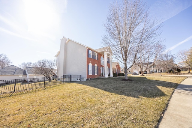 view of side of property with brick siding, a chimney, fence, and a yard