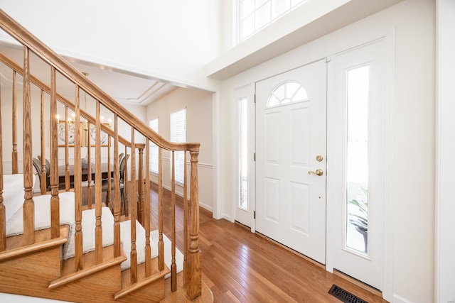 foyer with visible vents, stairway, and hardwood / wood-style flooring