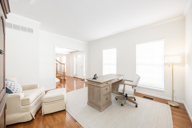 office featuring light wood-type flooring, baseboards, visible vents, and crown molding