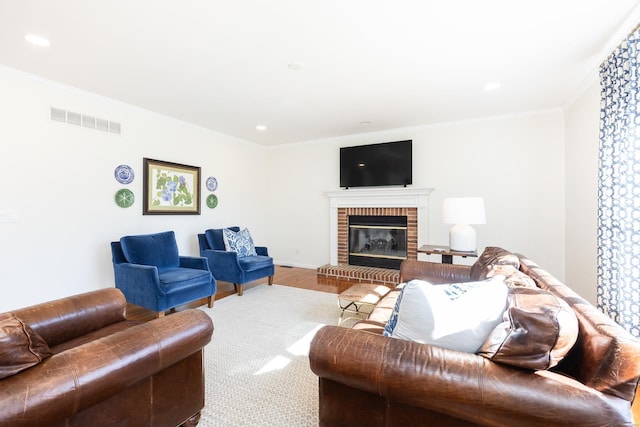 living room with visible vents, wood finished floors, crown molding, a fireplace, and recessed lighting