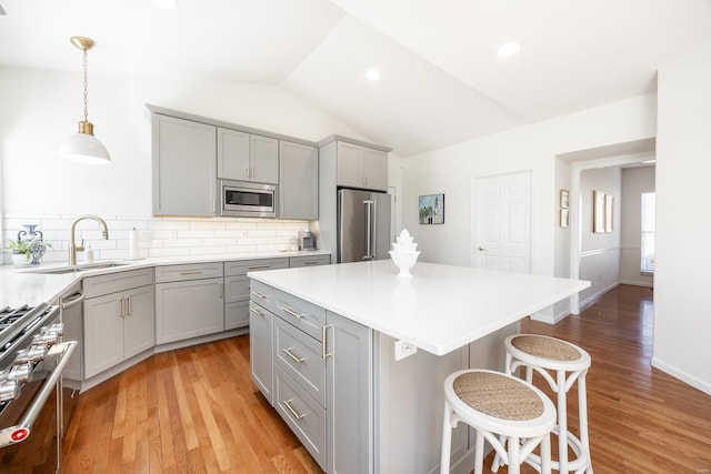 kitchen with appliances with stainless steel finishes, a breakfast bar area, a sink, and gray cabinetry