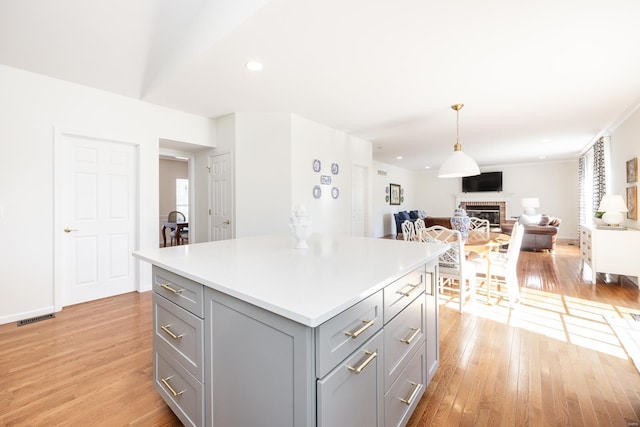 kitchen featuring light wood-type flooring, a brick fireplace, open floor plan, and gray cabinetry