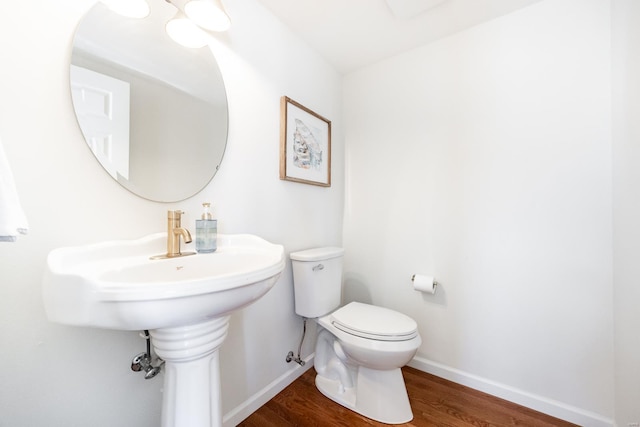 bathroom with baseboards, toilet, and wood finished floors