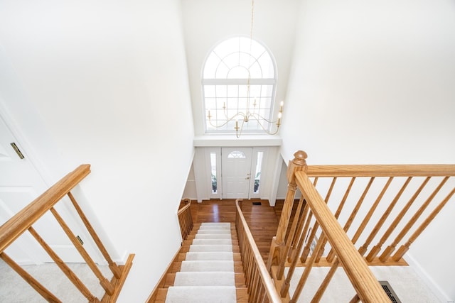 stairs with a towering ceiling, baseboards, and a chandelier