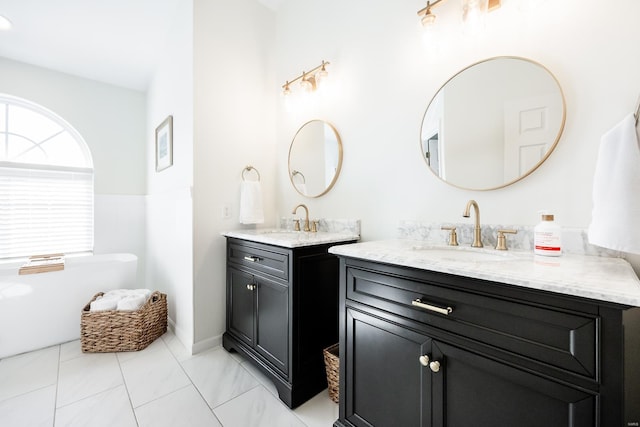 full bath with a freestanding bath, two vanities, and a sink