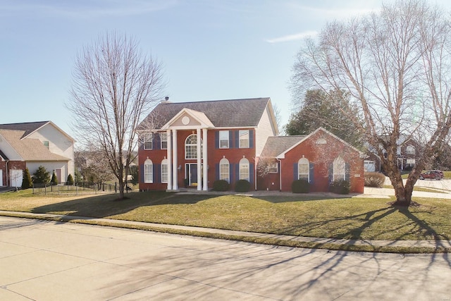 greek revival house with brick siding, fence, and a front lawn