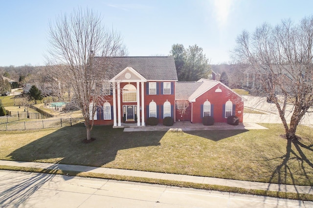 greek revival inspired property with fence, a front lawn, and brick siding