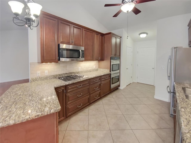 kitchen with light tile patterned floors, stainless steel appliances, vaulted ceiling, decorative backsplash, and light stone countertops