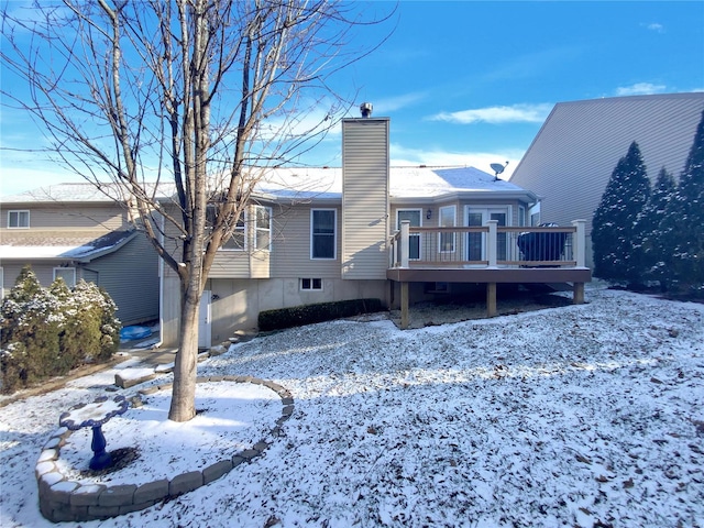 snow covered rear of property featuring a chimney and a deck