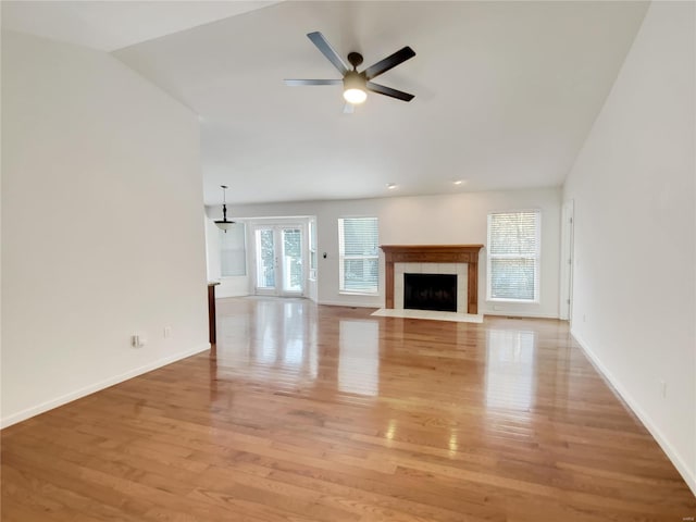 unfurnished living room with baseboards, light wood-style flooring, ceiling fan, vaulted ceiling, and a fireplace