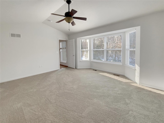 carpeted empty room with lofted ceiling, baseboards, visible vents, and a ceiling fan