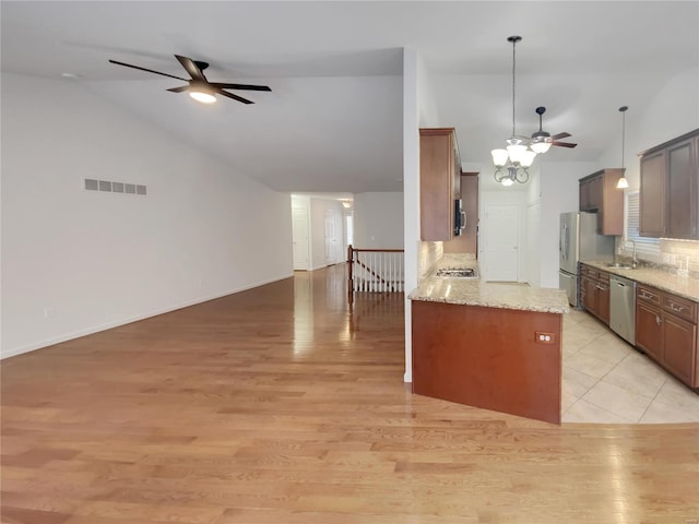 kitchen featuring visible vents, decorative backsplash, appliances with stainless steel finishes, open floor plan, and a sink