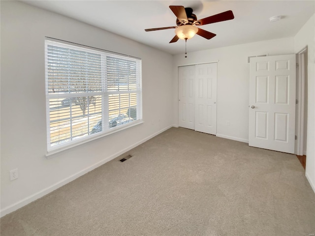 unfurnished bedroom featuring baseboards, visible vents, a ceiling fan, carpet floors, and a closet