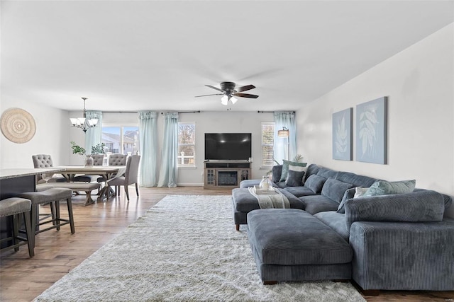 living room with ceiling fan with notable chandelier and wood finished floors