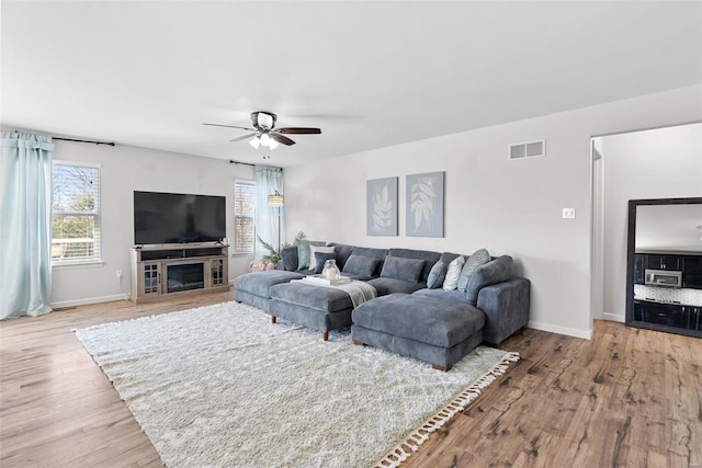 living room with visible vents, baseboards, wood finished floors, and a ceiling fan