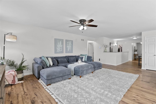 living area featuring visible vents, ceiling fan, baseboards, and wood finished floors