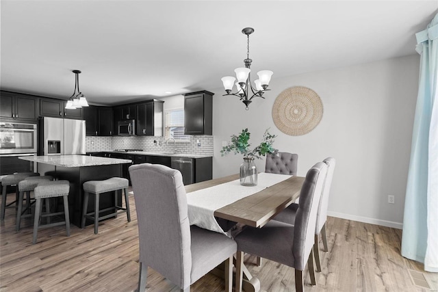 dining space featuring a chandelier, baseboards, and light wood-style flooring