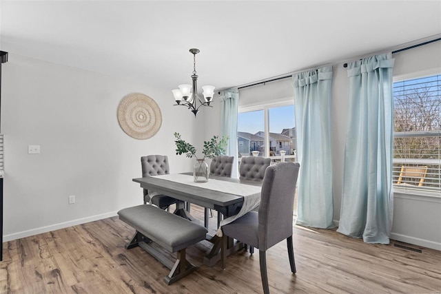 dining area featuring wood finished floors, baseboards, and a chandelier