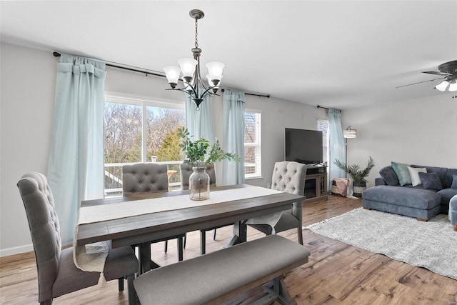 dining area featuring ceiling fan with notable chandelier and wood finished floors