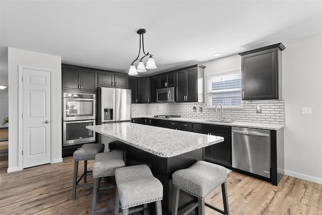 kitchen featuring a sink, a kitchen breakfast bar, a center island, stainless steel appliances, and decorative backsplash