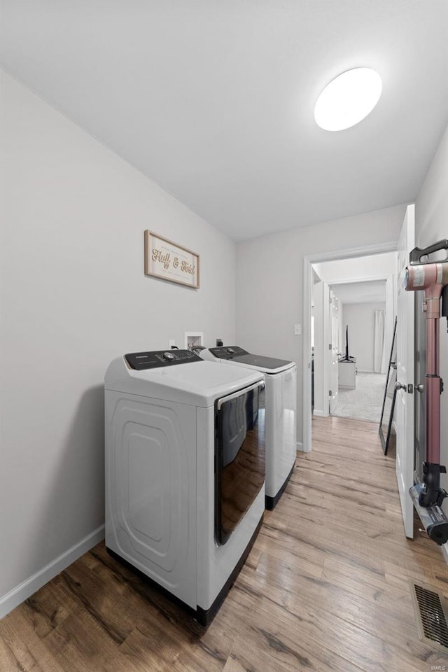 laundry area with washer and clothes dryer, laundry area, light wood-type flooring, and baseboards