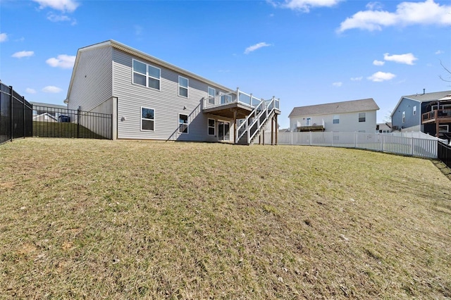 rear view of house featuring a deck, stairway, a lawn, and a fenced backyard