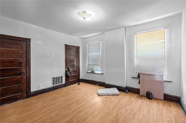 empty room with wood finished floors, visible vents, and baseboards