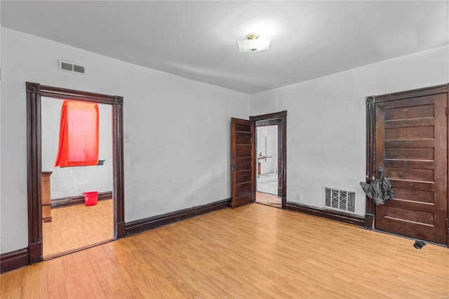 empty room featuring wood finished floors, visible vents, and baseboards