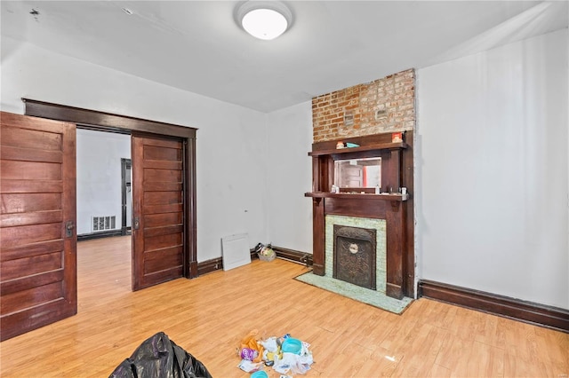 unfurnished living room featuring baseboards, a fireplace, visible vents, and wood finished floors