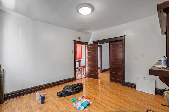 bedroom with baseboards, visible vents, and wood finished floors