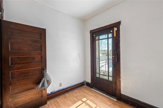 doorway to outside with baseboards and light wood-style floors