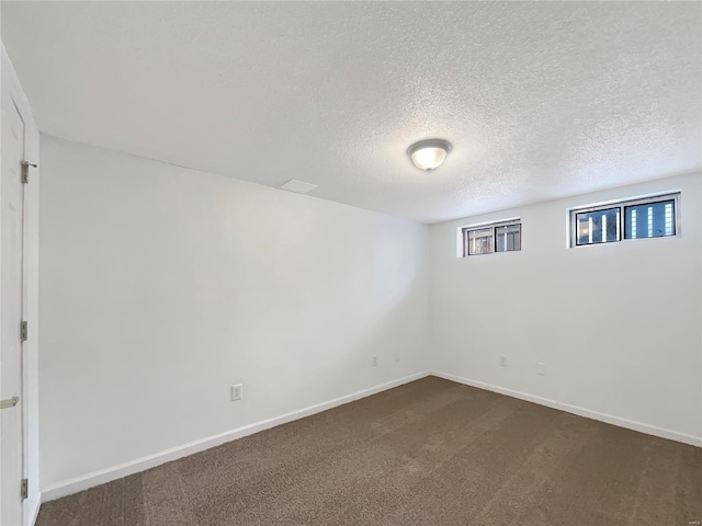 below grade area featuring dark carpet, a textured ceiling, and baseboards