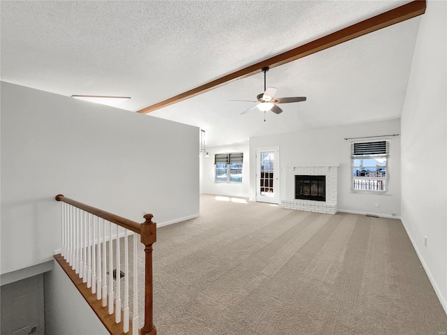 unfurnished living room with carpet, a fireplace, vaulted ceiling with beams, a ceiling fan, and a textured ceiling